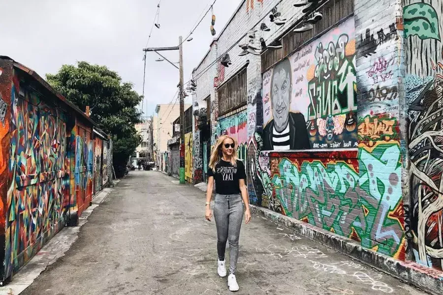 Una mujer camina por un callejón en el Distrito de la Misión que está cubierto de murales y obras de arte. San Francisco, California.